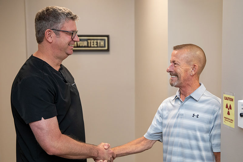 dental implant patient shaking hands with Dr. Rogers
